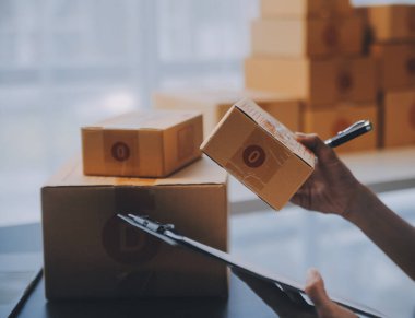 Küçük işletme girişimcisi ya da serbest çalışan, kutulu laptop kullanan Asyalı bir kadın, elini kaldıran genç başarılı Asyalı kadın, çevrimiçi pazarlama kutusu ve teslimatı, KME konsepti.