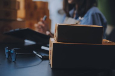 Küçük işletme girişimcisi ya da serbest çalışan, kutulu laptop kullanan Asyalı bir kadın, elini kaldıran genç başarılı Asyalı kadın, çevrimiçi pazarlama kutusu ve teslimatı, KME konsepti.