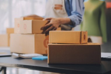 Küçük işletme girişimcisi ya da serbest çalışan, kutulu laptop kullanan Asyalı bir kadın, elini kaldıran genç başarılı Asyalı kadın, çevrimiçi pazarlama kutusu ve teslimatı, KME konsepti.