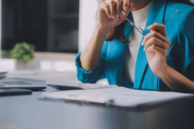 Bir ofis masası, vergi, rapor, muhasebe, istatistik ve analitik araştırma kavramında matematik finansmanı için hesap makinesi ve dizüstü bilgisayar kullanan Asyalı İş kadını