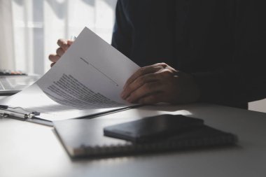 Asyalı işadamı ofis işyerindeki belge raporlarını bilgisayar laptopuyla inceliyor. Hukuk uzmanı, profesyonel avukat mali belgeleri okuyup kontrol ediyor ya da sigorta sözleşmesini.