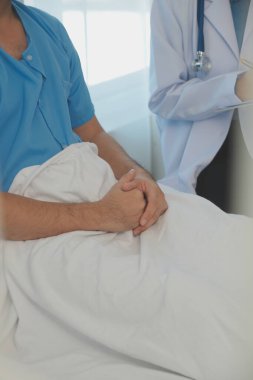Genç doktor steteskop kullanıyor. Hastanın kalp atışlarını dinle. Kadın bir doktorun erkek bir hastaya muayene yaparken görüntüsü.