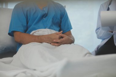Genç doktor steteskop kullanıyor. Hastanın kalp atışlarını dinle. Kadın bir doktorun erkek bir hastaya muayene yaparken görüntüsü.