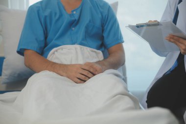 Genç doktor steteskop kullanıyor. Hastanın kalp atışlarını dinle. Kadın bir doktorun erkek bir hastaya muayene yaparken görüntüsü.