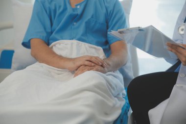 Genç doktor steteskop kullanıyor. Hastanın kalp atışlarını dinle. Kadın bir doktorun erkek bir hastaya muayene yaparken görüntüsü.