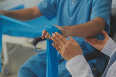 Hastaya direnç bandı takan fizyoterapist.