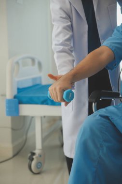 Egzersiz halter tedavi hakkında kol ve omuz sporcu ile erkek hastanın fizik tedavi kavramı veren fizyoterapist adam