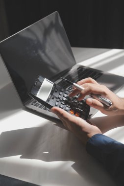 İş adamı masabaşında hesap makinesi kullanarak rakamları hesaplıyor ve muhasebe kavramını finanse ediyor.