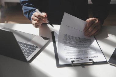 Asyalı işadamı ofis işyerindeki belge raporlarını bilgisayar laptopuyla inceliyor. Hukuk uzmanı, profesyonel avukat mali belgeleri okuyup kontrol ediyor ya da sigorta sözleşmesini.