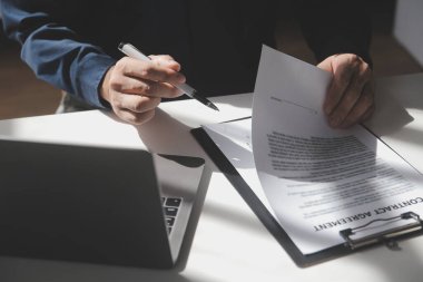 Asyalı işadamı ofis işyerindeki belge raporlarını bilgisayar laptopuyla inceliyor. Hukuk uzmanı, profesyonel avukat mali belgeleri okuyup kontrol ediyor ya da sigorta sözleşmesini.