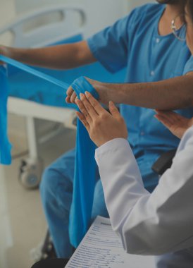 Hastaya direnç bandı takan fizyoterapist.