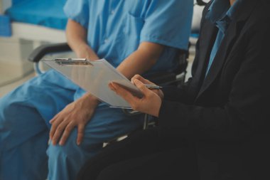 Kadın hemşirenin orta bölümü. Klinikte tekerlekli sandalyede oturan kadının tansiyonunu ölçüyor.