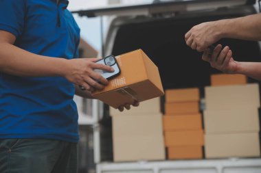 Asya teslimat ekspresi kuryesi genç adam, kadın müşteriye kutu veriyor. Evin önünde koruyucu yüz maskesi takıyor.