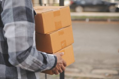 Asya teslimat ekspresi kuryesi genç adam, kadın müşteriye kutu veriyor. Evin önünde koruyucu yüz maskesi takıyor.