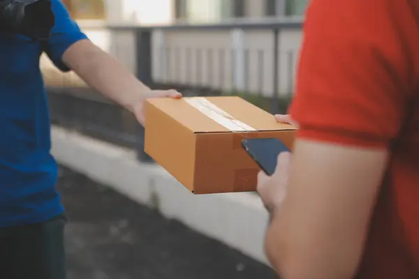 Asian delivery express courier young man use giving boxes to woman customer he wearing protective face mask at front home