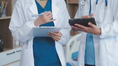 Kapalı. Hastanedeki bir hastanın masasına pano tutan ve reçete yazan kadın doktor..