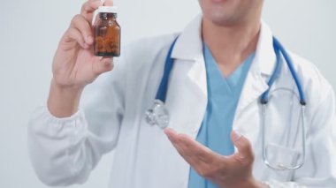 Steteskoplu genç bir doktor ve beyaz arka planda haplar, yakın plan.