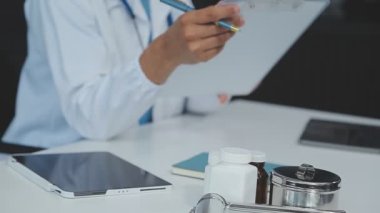 Doktor masadaki hasta için reçete yazıyor, tıbbi geçmişi var.