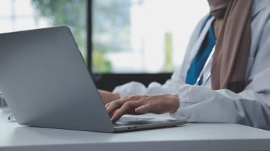 Laptop bilgisayar kullanan tıp üniformalı doktor.