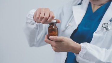 Doktor elinde bir şişe ilaç tutuyor.