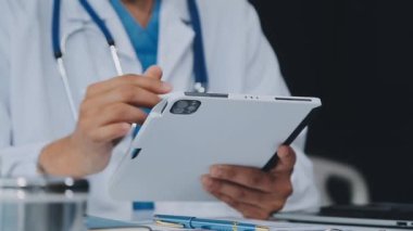 Doktor tablet tutuyor ve steteskop kullanıyor. Doktor klinikte dijital tabletle çalışıyor. Sağlık ve Tıp Konsepti.