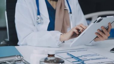 Ofiste dizüstü bilgisayar ve dijital tabletle çalışan kadın doktor