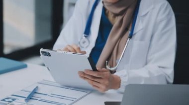 Doktor Eli 'ni kapatın tableti tutun ve masasında kalemle kağıda yazın. Tıbbi Sağlık Hizmetleri