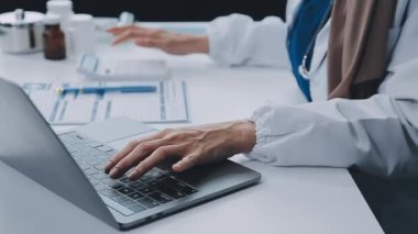 Ofisinde dizüstü bilgisayarı olan genç bir doktor.
