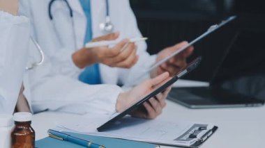 Doktor elinde tablet bilgisayarla hastasıyla çalışıyor..