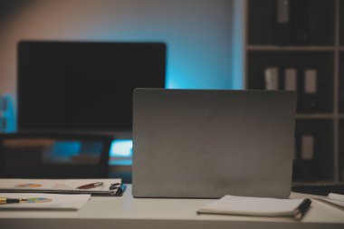 Laptop ve evraklar konferans masasında.