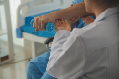 Egzersiz halter tedavi hakkında kol ve omuz sporcu ile erkek hastanın fizik tedavi kavramı veren fizyoterapist adam