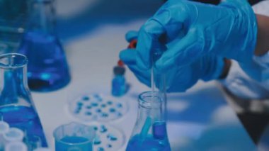 Koruyucu gözlüklü bilim adamı elinde kimyasal sıvıyla tüpü tutuyor