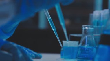 Kimya laboratuvarı. Elinde mavi sıvı bulunan laboratuvar test tüpü..