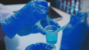 Laboratuvarda elinde sıvı olan bir tüp tutan bilim adamının resmi.