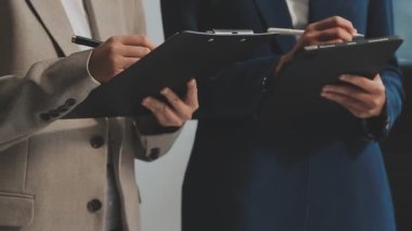 Yakın plan. İki iş adamı el ele tutuşuyor ve modern ofiste masada bir şeyler tartışıyorlar..
