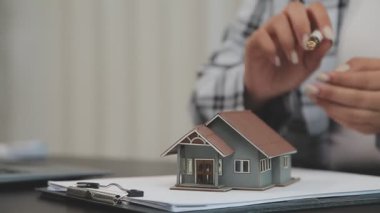 Emlakçı evin anahtarını ve modelini tutuyor.