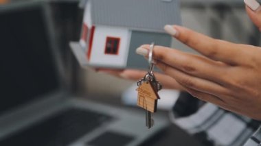 Elinde model bir ev ve anahtar tutan bir kadın.