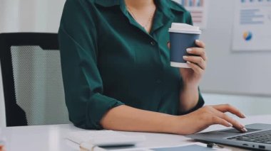Bilgisayarda çalışırken elinde kahve bardağıyla iş kadınının fotoğrafını çek.