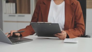 Ofiste tablet bilgisayar kullanan günlük kıyafetli genç bir kadının kesilmiş fotoğrafı.