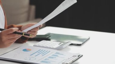 Genç Asyalı iş adamı hesap makinesi tutuyor ve yatırım için finansman hesaplıyor.