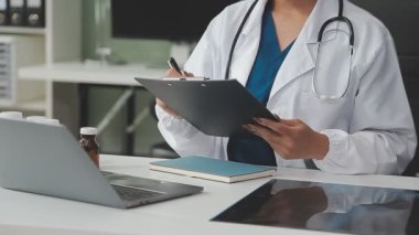 Bir doktorun elinde steteskopla tablet bilgisayarı tutarken.
