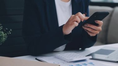 Ofisinde kredi kartıyla cep telefonu kullanan genç bir kadın.