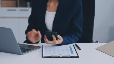 Ofiste dizüstü bilgisayar ve akıllı telefonla çalışan bir kadın.