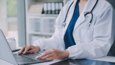 Elinde tablet ve bilgisayarla beyaz önlüklü genç bir bayan doktor..