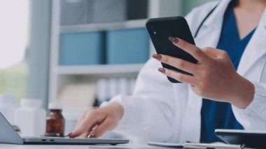 Genç bayan doktor hastanede akıllı telefon kullanıyor.