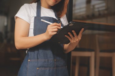 Başlangıçta başarılı olan küçük işletme sahibi, kafeterya restoranında elinde tablet akıllı telefonuyla güzellik kızı standı açmıştı. Kahveci Asyalı kadının portresi. KOBİ girişimci iş konsepti