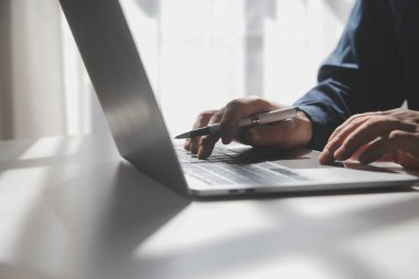 Bir kahve dükkanında dizüstü bilgisayarı üzerinde çalışan genç bir adamın kırpılmış görüntüsü, iş adamının elleri ofis masasında dizüstü bilgisayarla meşgul, genç bir erkek öğrenci ahşap masada oturuyor.