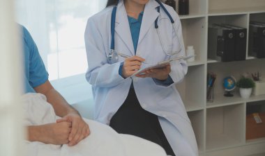 Genç doktor steteskop kullanıyor. Hastanın kalp atışlarını dinle. Kadın bir doktorun erkek bir hastaya muayene yaparken görüntüsü.