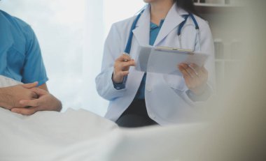 Genç doktor steteskop kullanıyor. Hastanın kalp atışlarını dinle. Kadın bir doktorun erkek bir hastaya muayene yaparken görüntüsü.