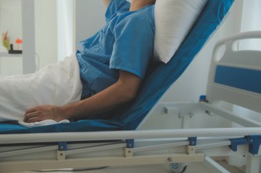 Hastanede bir yatakta yatan ciddi hasta adam. Monitörler yaşam belirtilerini gösteriyor. Ward's temiz ve yeni.